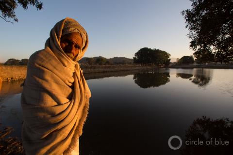 A man stands in front of a small lake in Punjab, India