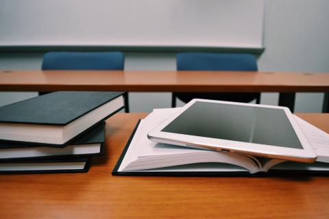 stack of books and a tablet on a desk