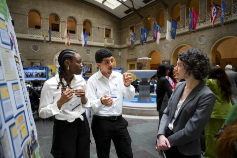 Two students presenting a research poster to an evaluator 