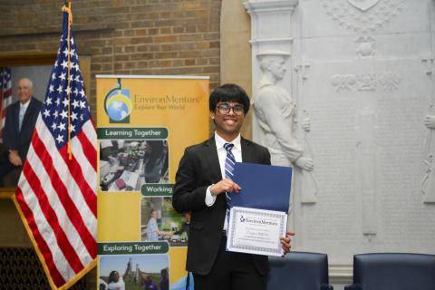 Young man on stage holding award certificate