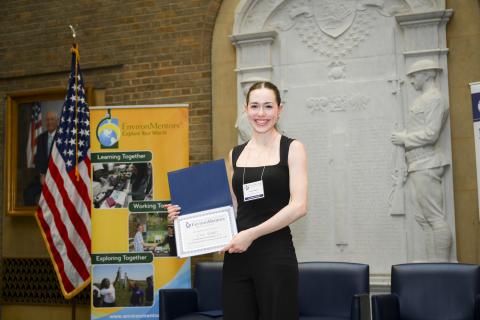 Young woman on stage with award certificate 