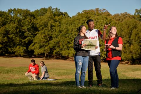 NC State students in a park area, looking at a map.