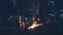A group of people gather around a campfire
